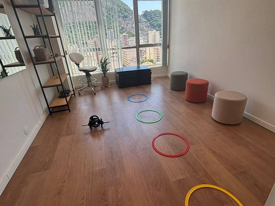 Sala de atividades com colchonetes, arcos coloridos e vista para o morro